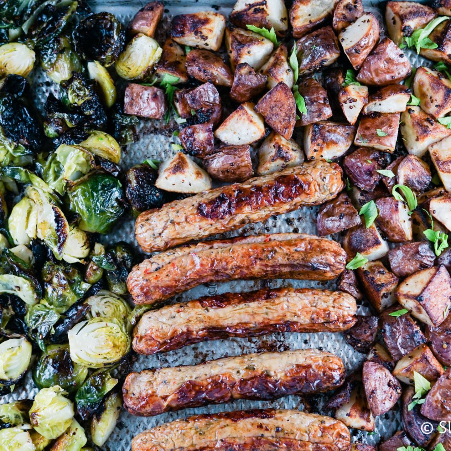 Sheet pan sausage with potatoes and Brussels sprouts on a sheet pan. 