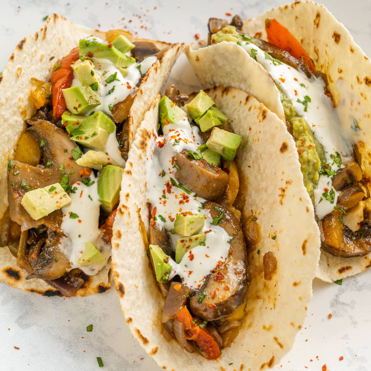 Portobello mushroom fajitas with peppers, onions, mushrooms, guacamole, and sour cream in a warm corn tortilla.