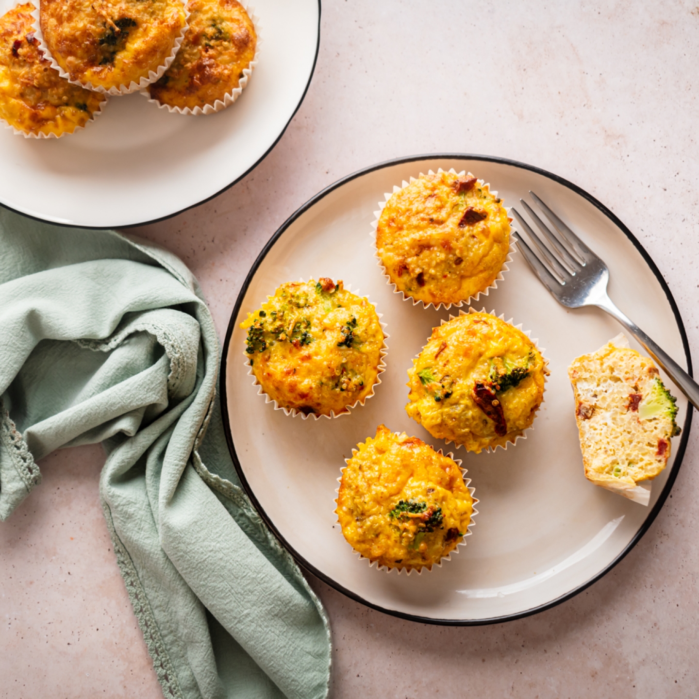 Quinoa egg muffins with cooked quinoa, eggs, broccoli, sundried tomatoes, and shredded cheese served on a plate.