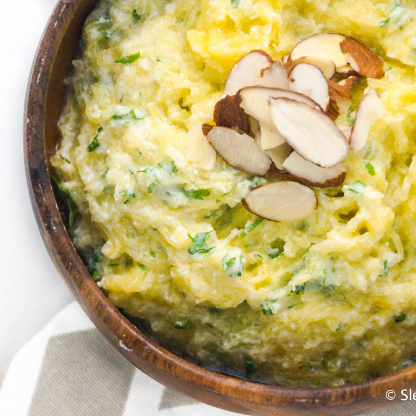 Creamy ricotta spaghetti squash in a wooden bowl with fresh basil on top.