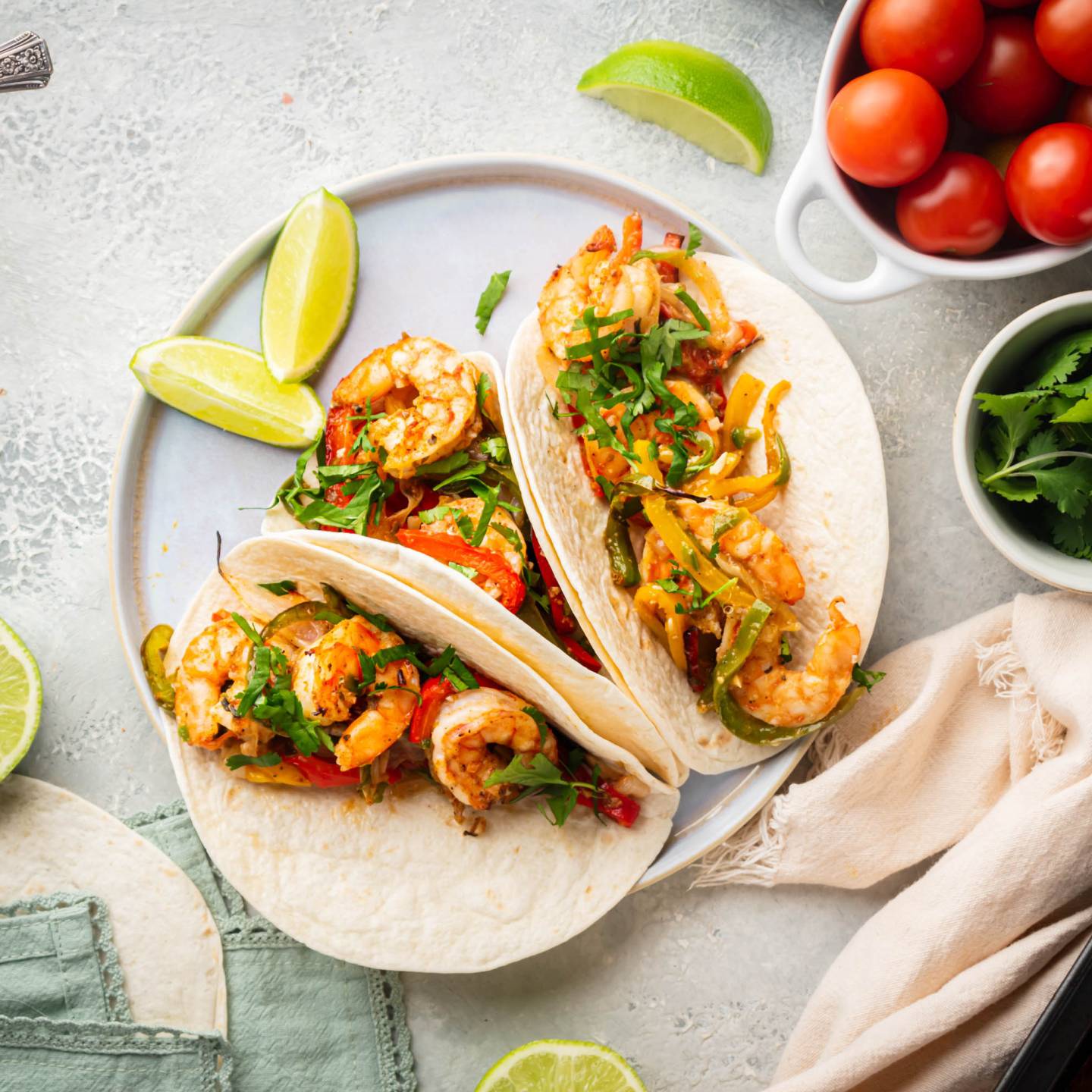 Sheet pan shrimp fajitas with peppers and onions served on flour tortillas with lime and cilantro.