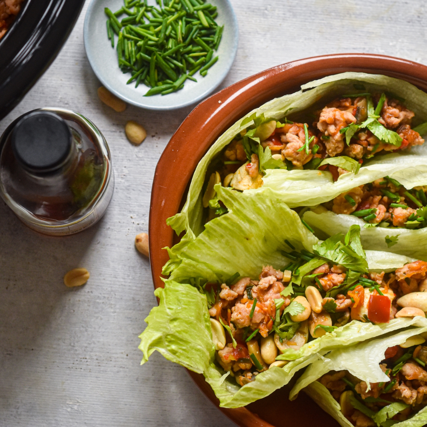 Slow cooker chicken lettuce wraps on a plate with lettuce leaves stuffed with chicken, mushrooms, peppers, and cilantro.