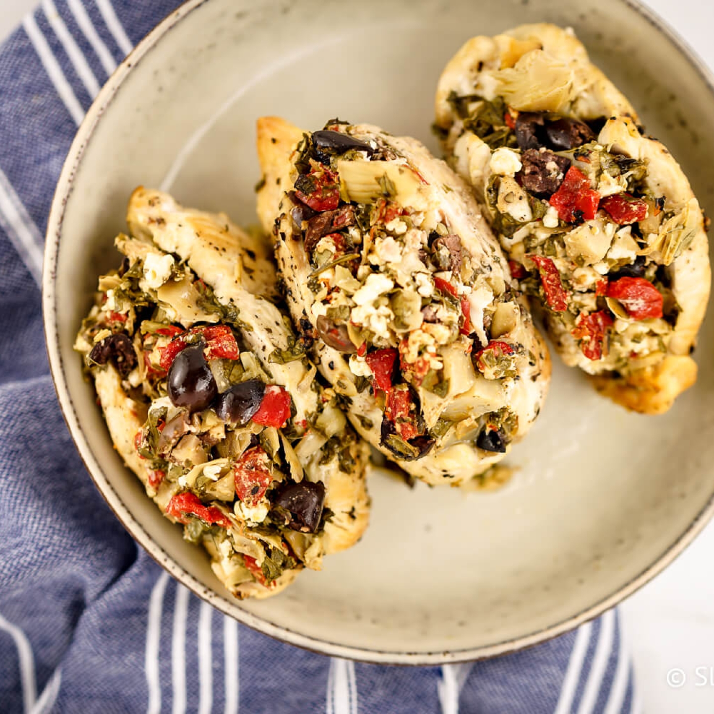 Skow Cooker Greek Chicken Breats stuffed with feta, olives, spinach, red peppers, and artichoke hearts.