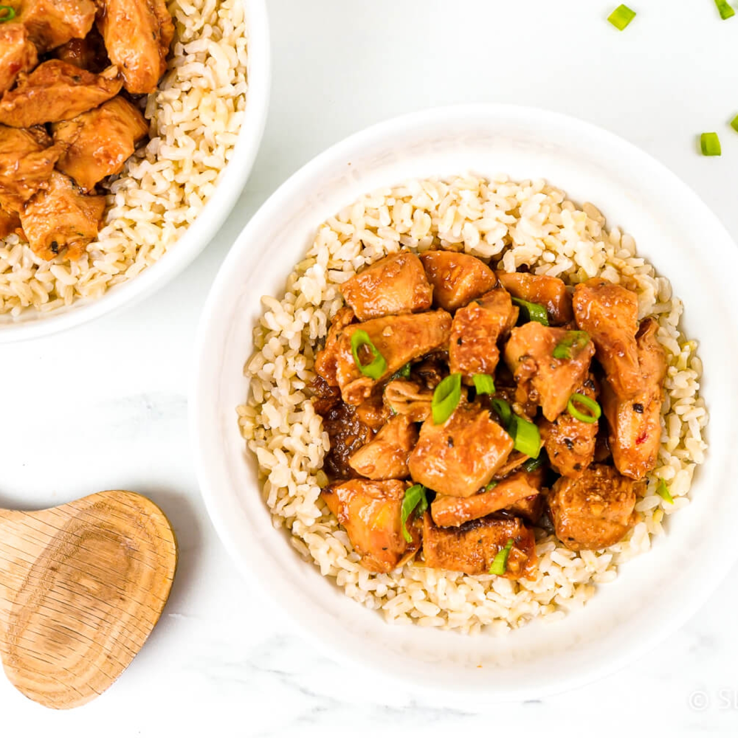 Slow cooker honey garlic chicken with green onions over a bed of brown rice