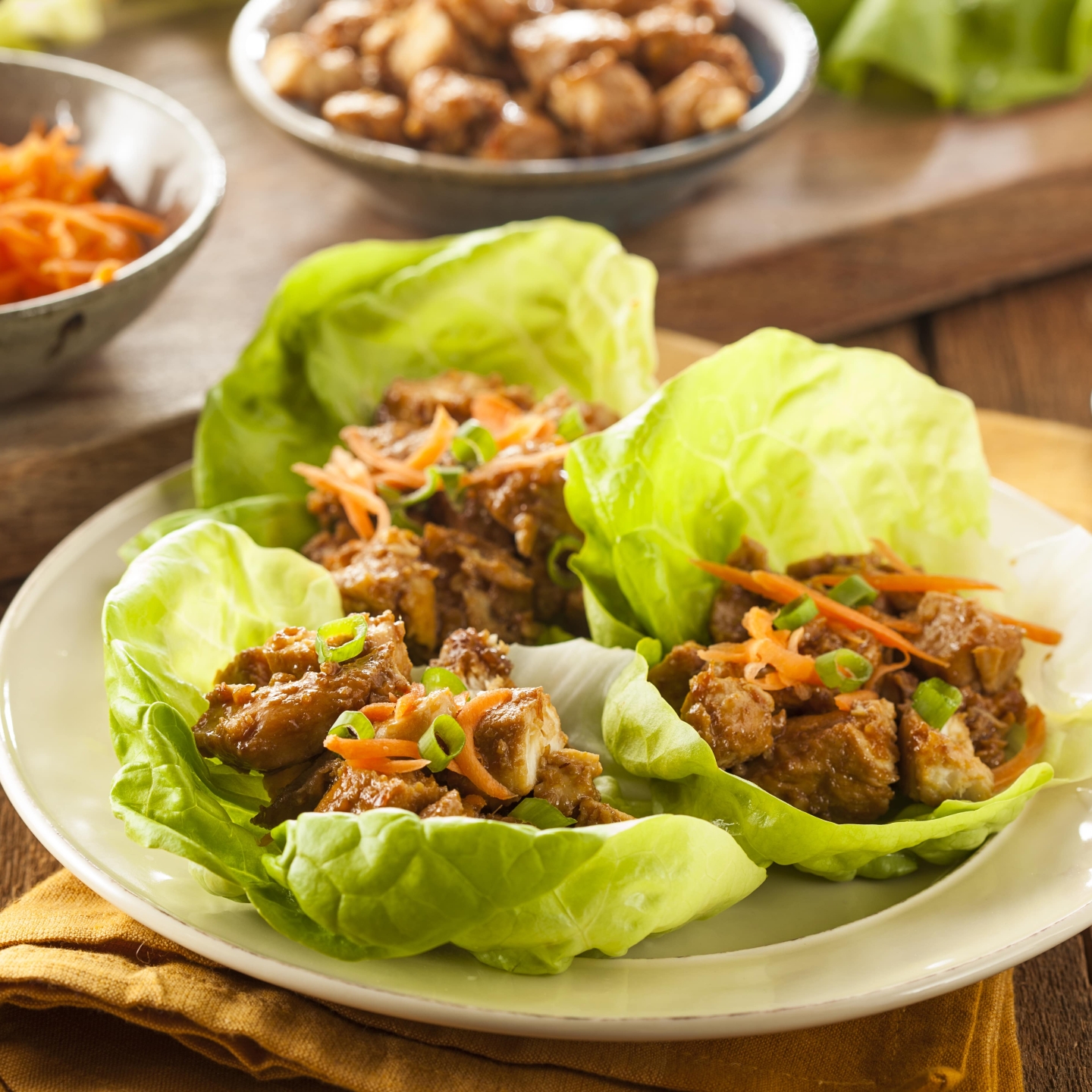 Slow Cooker Korean Chicken in lettuce wraps with shredded carrots on top.