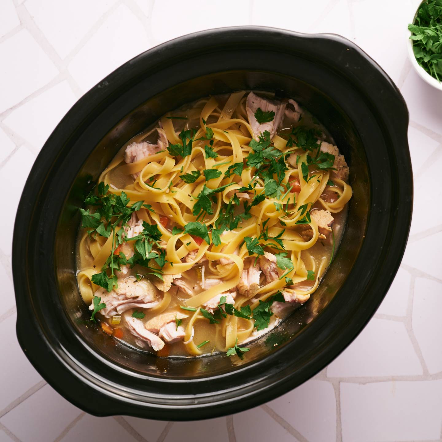 Slow cooker turkey soup with shredded turkey breast, egg noodles, carrots, celery, and onions.