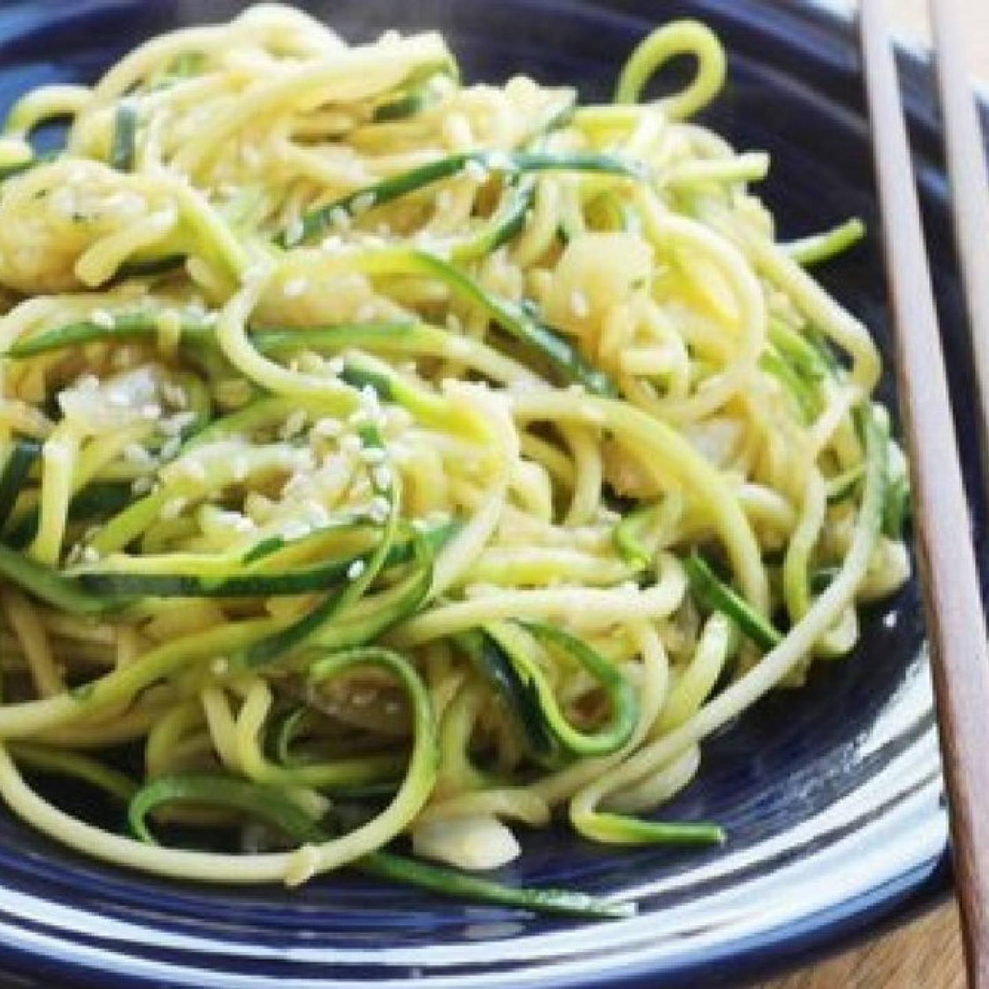 Stir Fried zucchini noodles on a plate with sesame seeds.