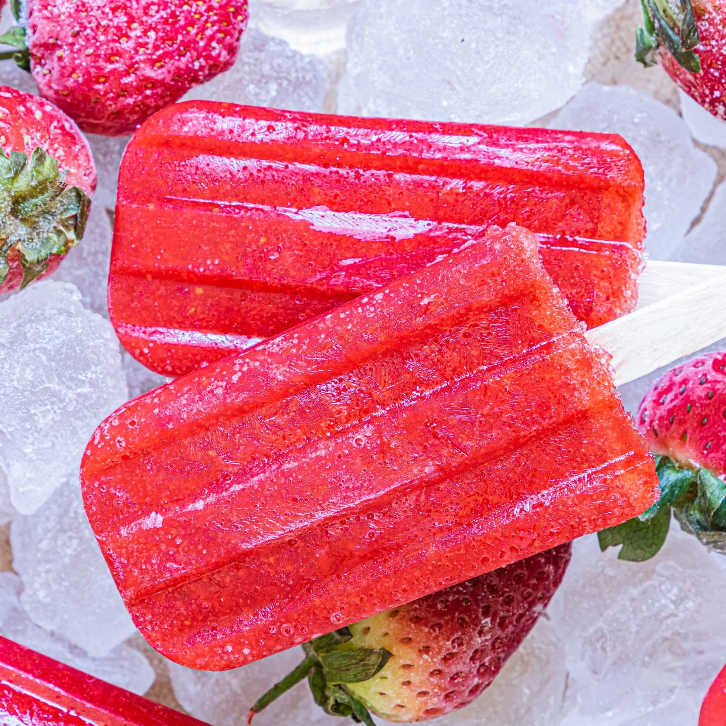 Strawberry popsicles made with fresh strawberries and honey served on a plate with ice.