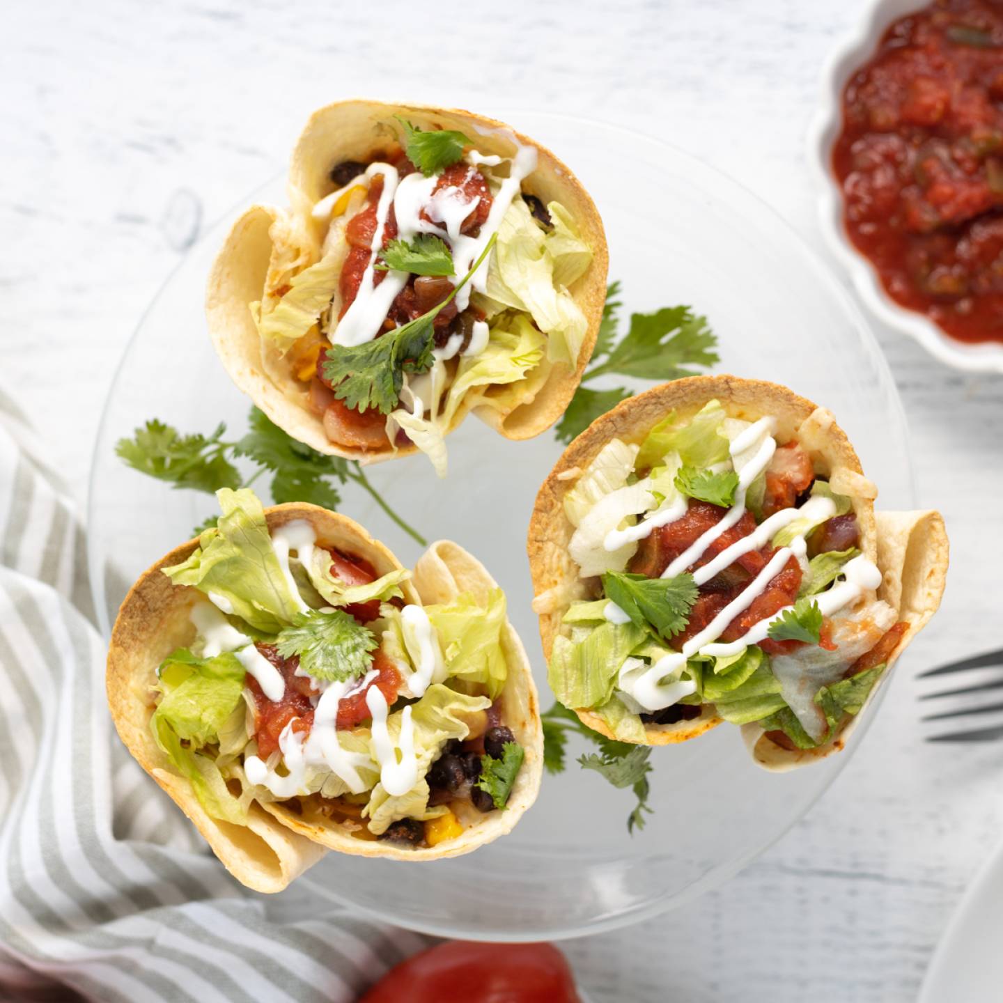 Taco cups with beans, corn, peppers, onions, salsa, and cheese in tortilla cups.