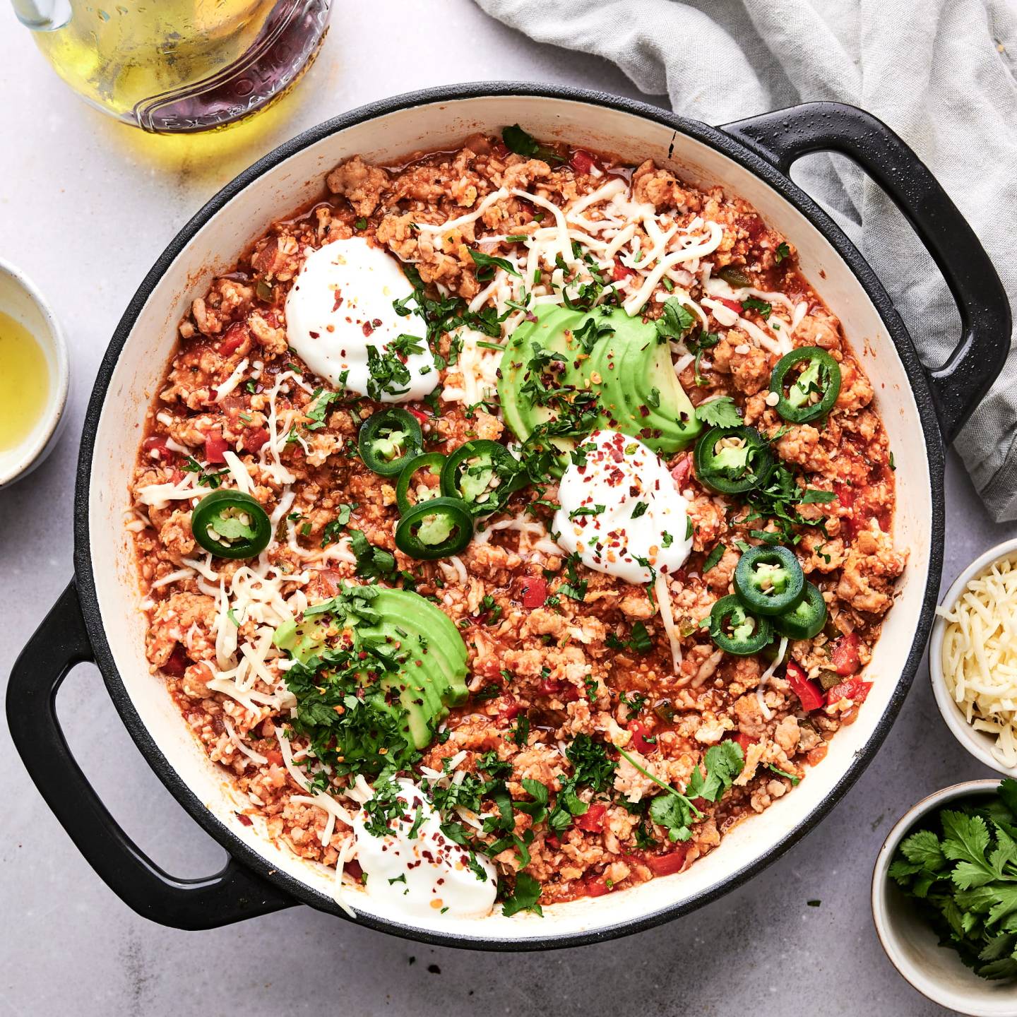 Ground turkey and cauliflower rice taco skillet with jalapenos, sour cream, cilantro, and lime wedges.