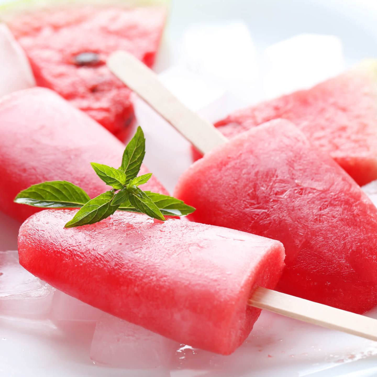 Two watermelon popsicles with a block of ice.