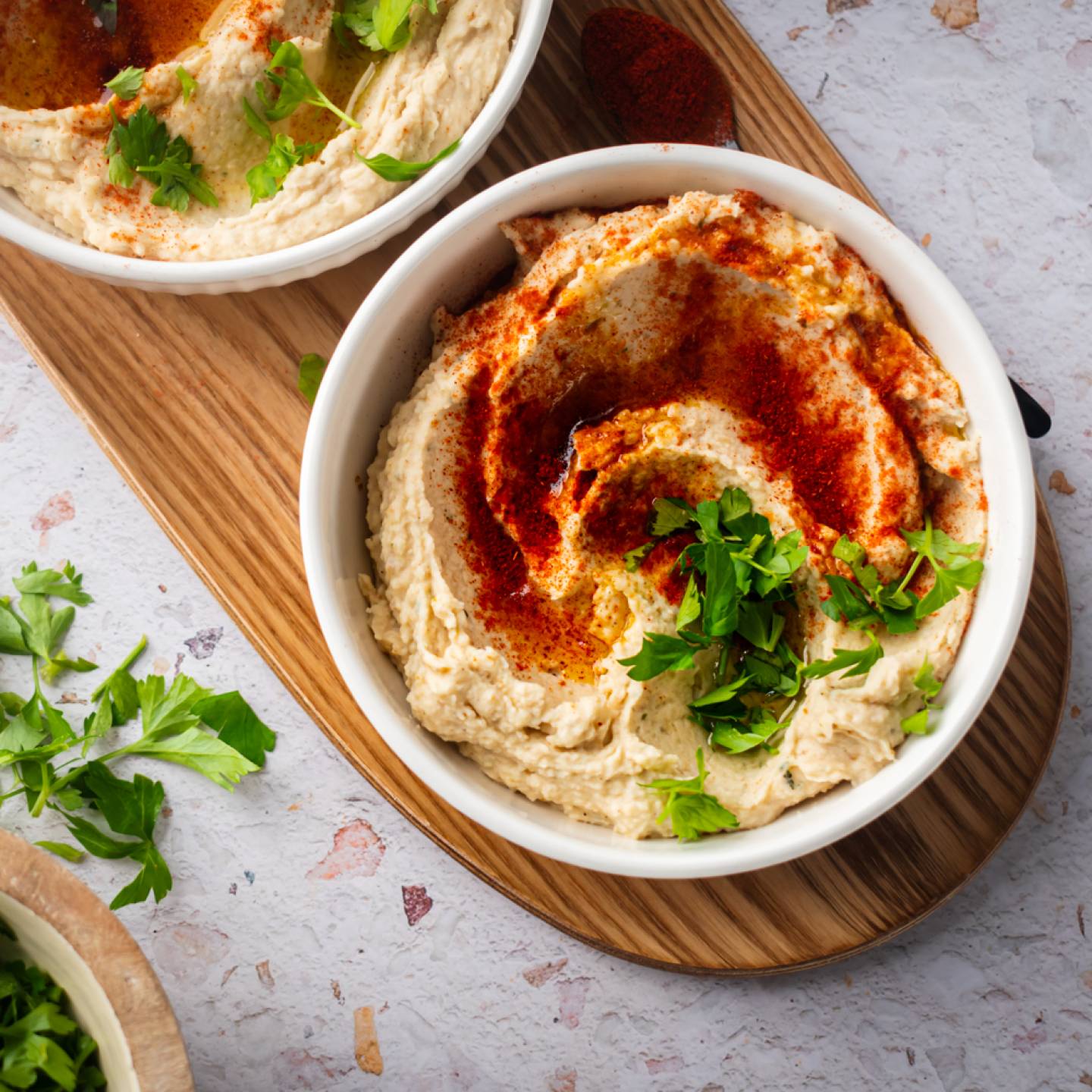 White bean hummus served in a bowl with olive oil, paprika, and fresh herbs.