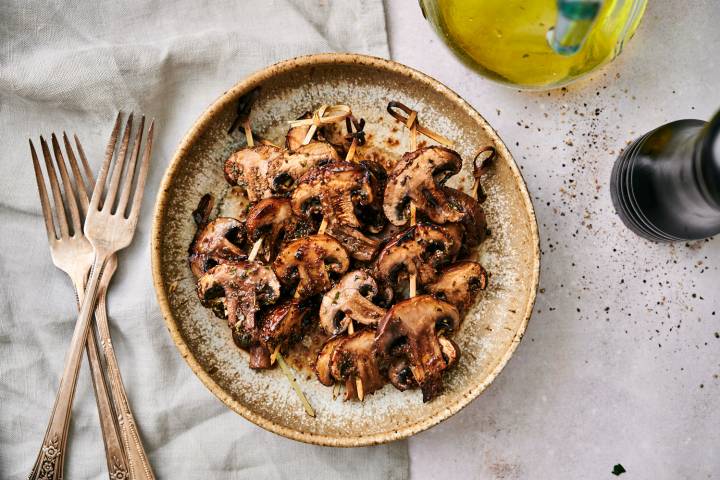 Grilled mushrooms with balsamic vinegar, olive oil, and garlic powder on a plate.