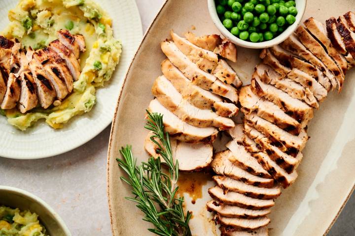Grilled turkey breast tenderloin served with maple mustard marinade on a plate with peas and rosemary.