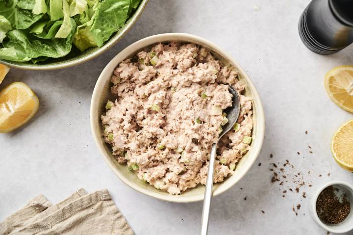 Healthy tuna salad with celery in a bowl with lettuce on the side.