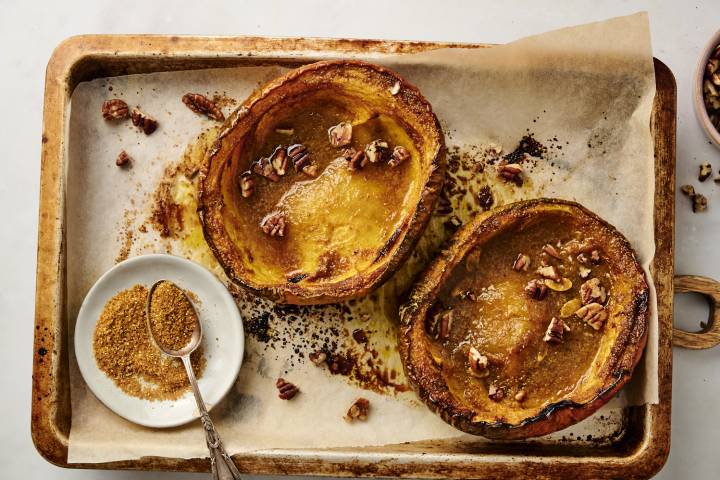 Roasted acorn squash with butter, brown sugar, and cinnamon on a baking sheet.