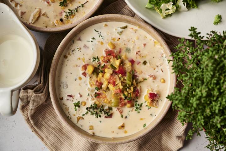 A bowl of creamy slow cooker roasted corn chowder topped with roasted vegetables, fresh thyme, and black pepper.