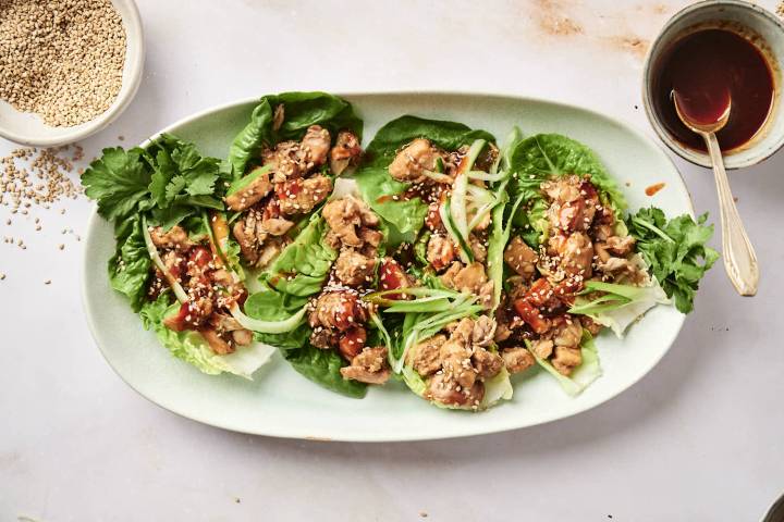 Slow Cooker Korean Chicken in lettuce wraps with sesame seeds and green onions on top.