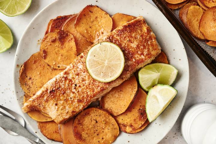 Spiced salmon fillet with a lime slice, served over roasted sweet potatoes.