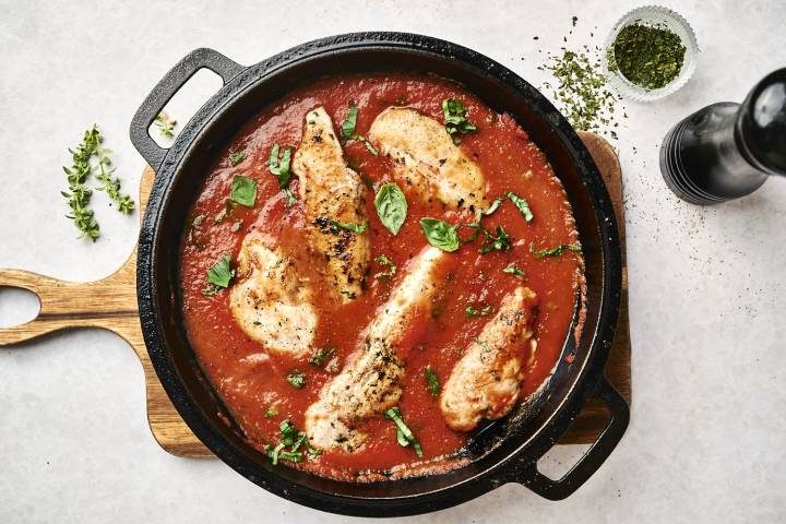 Tomato basil chicken with chicken breast served in a hearty tomato sauce with basil in a heavy skillet.