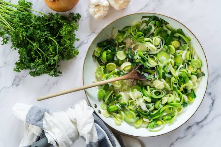 Leeks and onions cooking in a skillet.