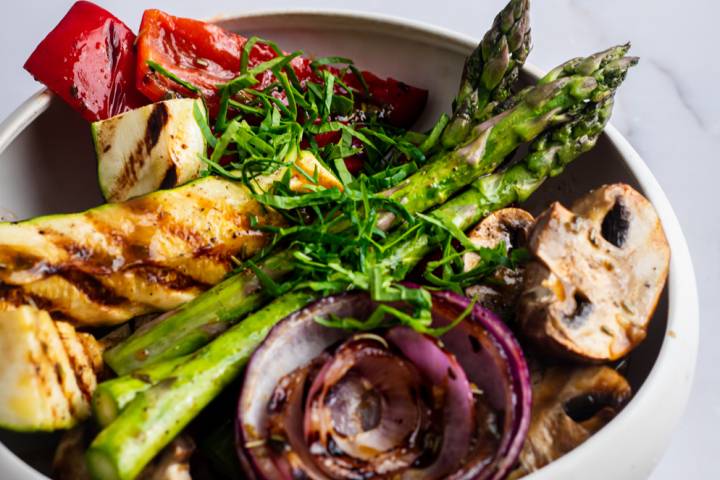 Grilled vegetables in a white bowl with balsamic marinade.