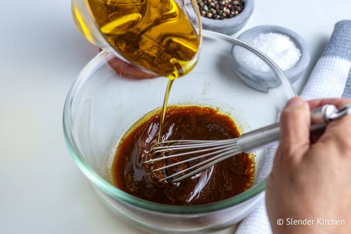 Oil being whisked and emulsified in balsamic vinegar dressing. 