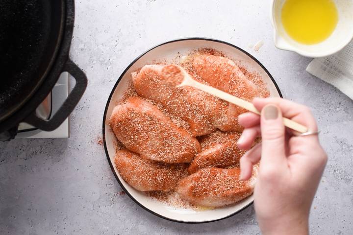 Chicken breast being coated in blackening seasoning.