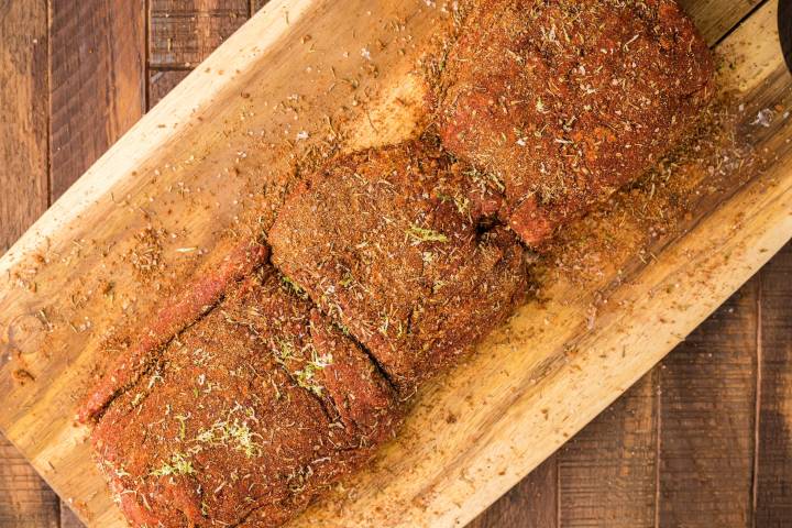 Steak covered in blackening seasoning on a cutting boad.