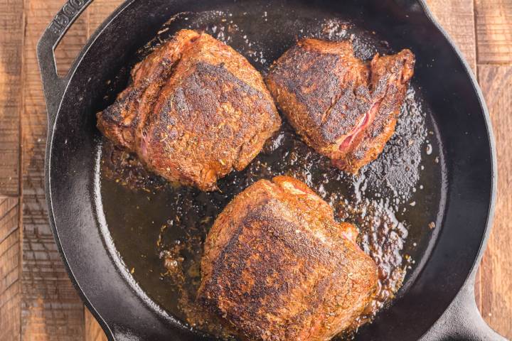 Steak being blackened in a cast iron skillet.