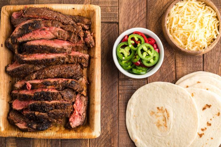 Slcied blackened steak with flour tortillas, cheese, and jalapenos for tacos.