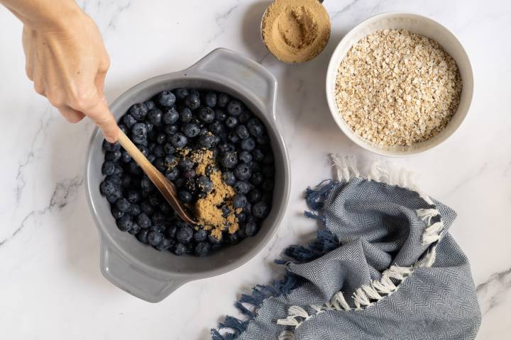 Blueberries being stirred with brown sugar and balsamic vinegar.