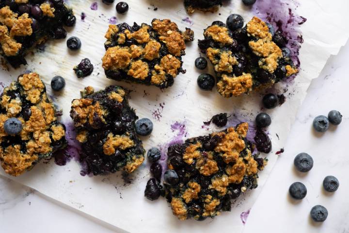 Baked blueberry oat bars cut into squares on parchment paper.