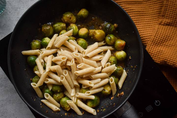 Brussels sprouts pasta with bacon in a skillet.