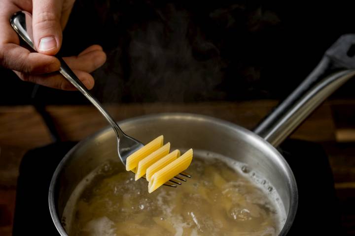 Penne being cooked in boiling water.