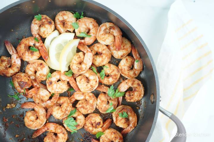 Cajun shrimp in a pan with lemon and parsley.