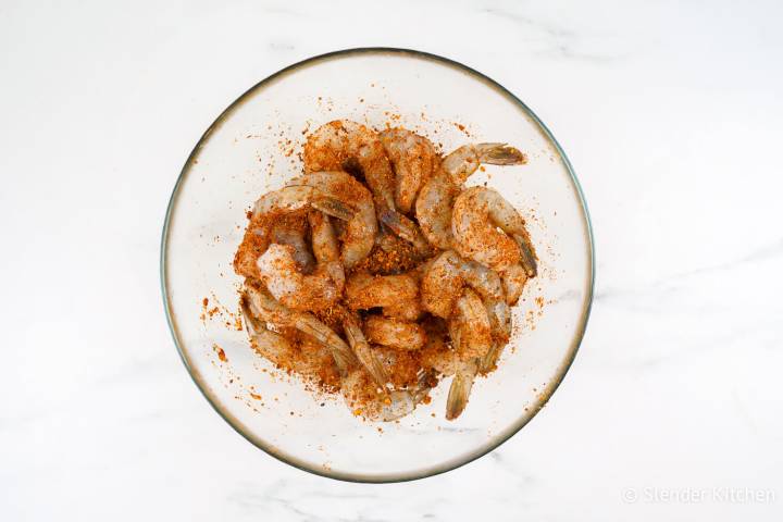 Raw shrimp in a bowl with Cajun seasoning.