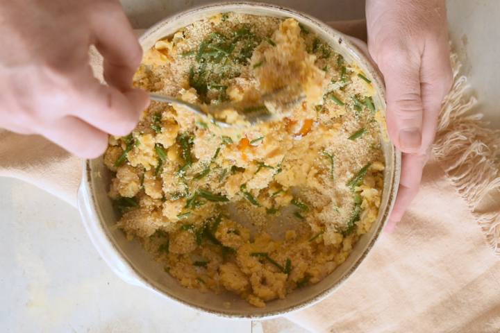 Chickpeas, breadcrumbs, ranch seasoning, and green onions being mixed in a bowl for burgers.