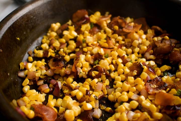 Corn, bacon, onions, and jalapenos cooking in a skillet.