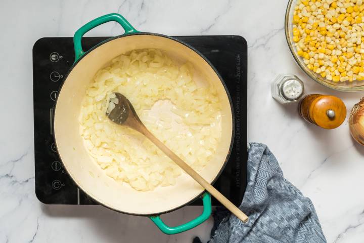 Onions, garlic, and butter cooking in a heavy soup pot.