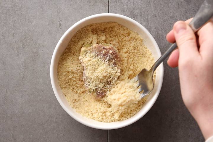 Pork chops being dredged in almond meal breading.