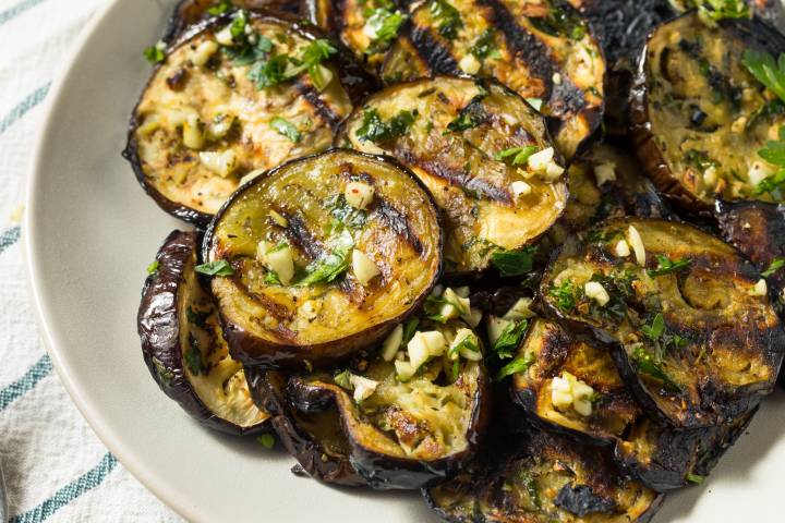 Garlic grilled eggplant on a plate with parsley and olive oil