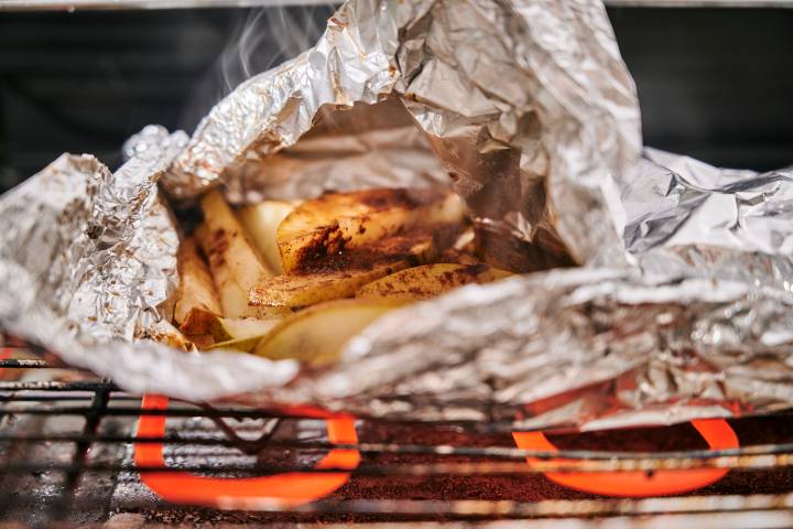 Sliced pears in a foil packet cooking on the grill. 