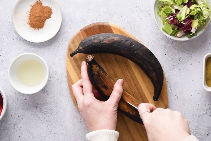 Plantains being sliced in half. 