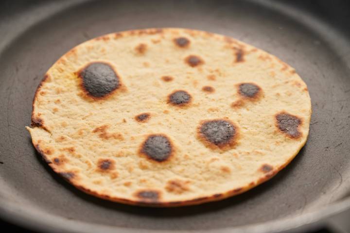 Tortillas on a griddle with charred marks.