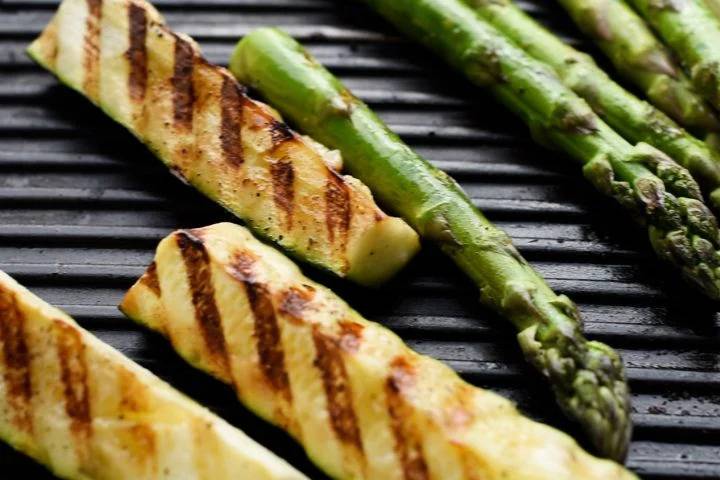 Zucchini and asparagus cooking on a grill plan.