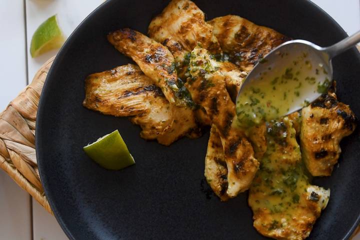 Honey lime sauce being drizzled on grilled chicken breast.