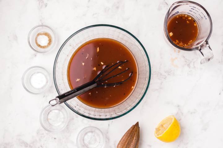 Flank steak marinade with garlic, lemon, Worcestershire sauce, and hot sauce in a bowl.