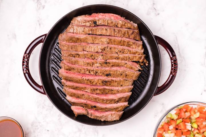 Flank steak grilled to medium rara and sliced on a pan.