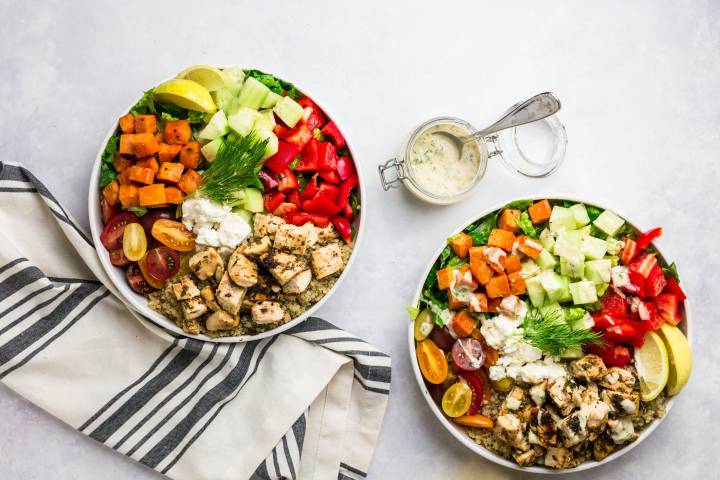 Mediterranean chicken bowls with vegetables, sweet potatoes, and dressing.